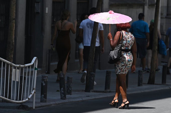 Una muer pasea con una sombrilla por el centro de Madrid
