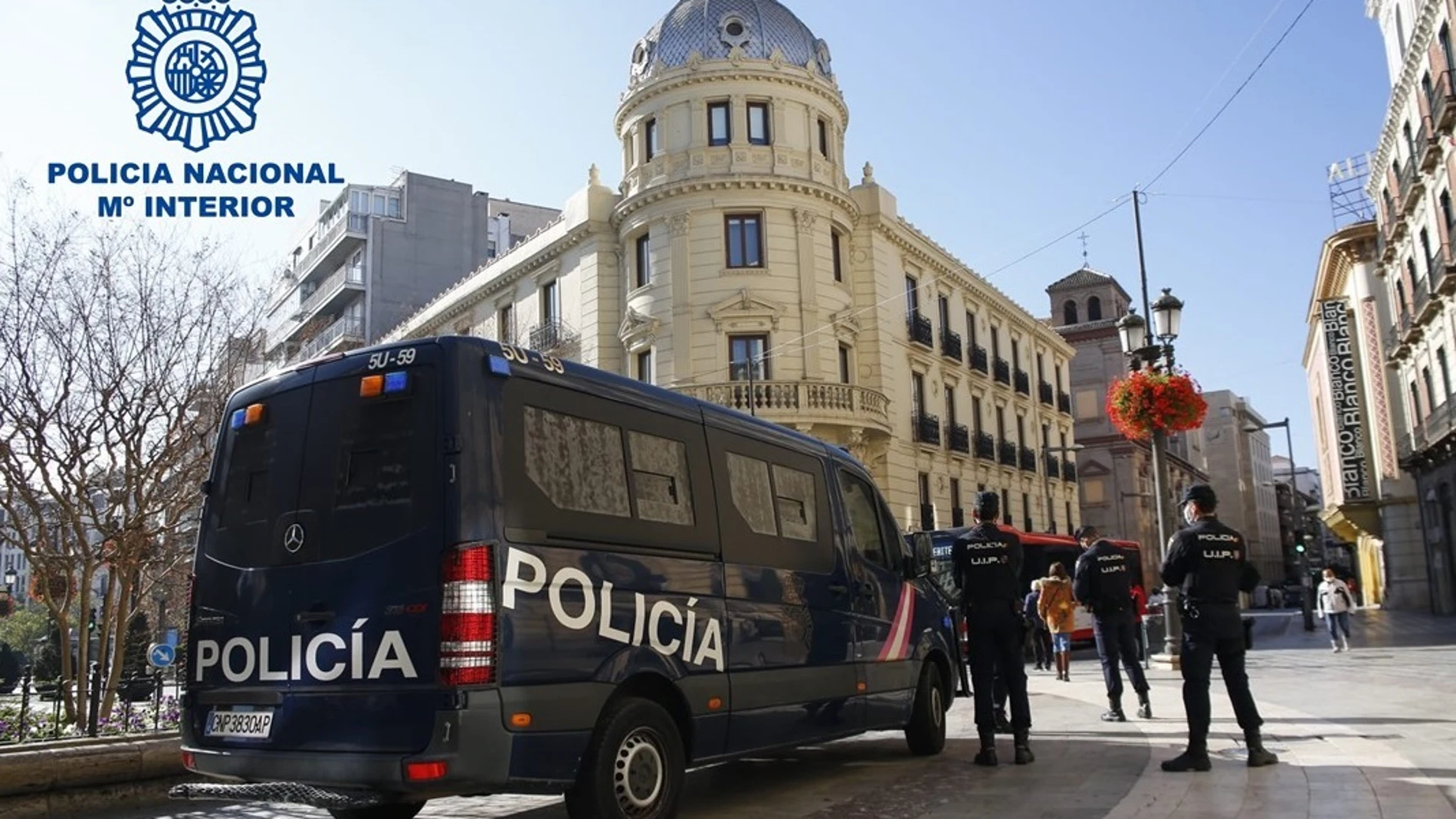 Agentes de la Policía, junto a un vehículo del cuerpo, en Granada