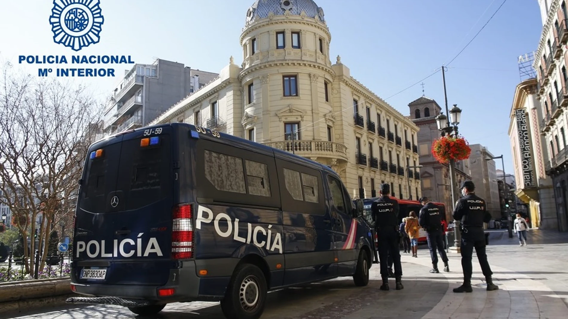 Agentes de la Policía, junto a un vehículo del cuerpo, en Granada
