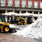 Dos máquinas excavadoras colaboran en la limpieza de la Plaza Mayor de Madrid