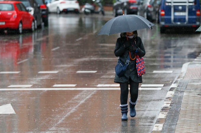 Una mujer camina bajo la lluvia por las calles de Madrid