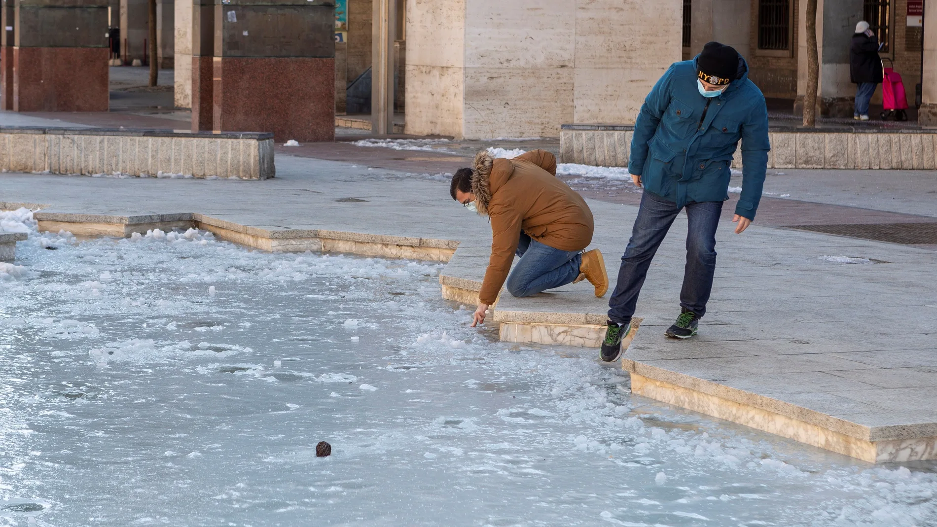 ZARAGOZA - Un par de curiosos comprueban en el espesor del hielo que cubre una fuente de Zaragoza. EFE/Javier Belver