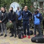 Una fila de rusos reclutados para la guerra de Ucrania reciben la bendición de un sacerdote ortodoxo