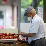 Imagen de una persona mayor comprando en una frutería