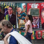Varias personas caminan frente a un puesto callejero de toallas con imágenes del actual presidente de Brasil y candidato a la reelección, Jair Bolsonaro, y su contendiente, el expresidente brasileño Lula da Silva, en Río de Janeiro