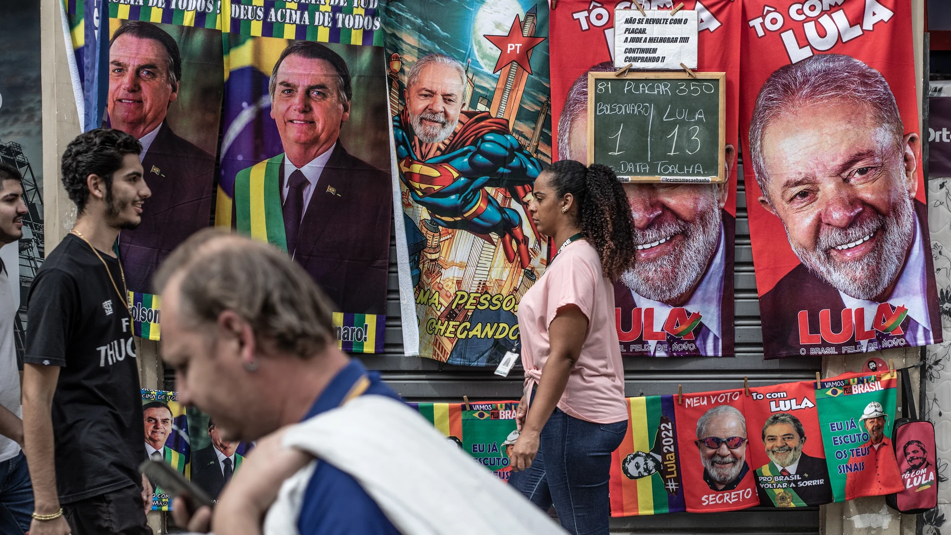 Varias personas caminan frente a un puesto callejero de toallas con imágenes del actual presidente de Brasil y candidato a la reelección, Jair Bolsonaro, y su contendiente, el expresidente brasileño Lula da Silva, en Río de Janeiro