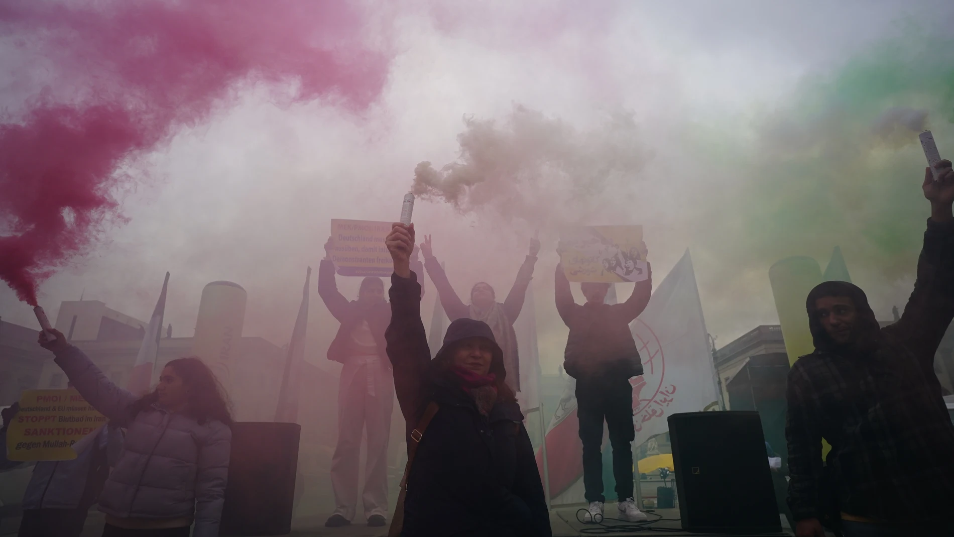 Manifestantes sostienen fuegos artificiales con los colores nacionales de Irán durante un mitin de "Solidaridad con el levantamiento civil en Irán" en la plaza Bebel Platz de Berlín