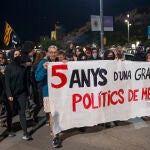Miembros del CDR Girona portan una pancarta que dice "cinco años de una gran estafa. Políticos de mierda" durante una manifestación con motivo del quinto aniversario del referéndum del 1-O.