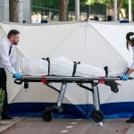 Dos trabajadores de la funeraria levantan el cadáver del joven asesinado en las inmediaciones de la discoteca "Caña Brava"