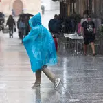 Una mujer se protege de la lluvia con un chubasquero, en la calle Trapería de Murcia