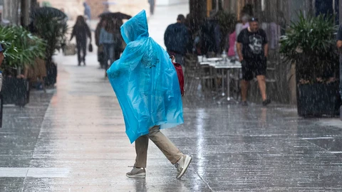 Una mujer se protege de la lluvia con un chubasquero, en la calle Trapería de Murcia