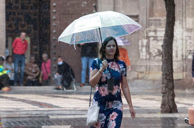 Una mujer se protege de la lluvia con un paraguas en la calle Trapería de Murcia