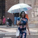 Una mujer se protege de la lluvia con un paraguas en la calle Trapería de Murcia