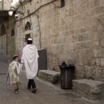 Un padre y un hijo judíos con mantones de oración caminan juntos en la Ciudad Vieja de Jerusalén en Yom Kippu, 5 de octubre de 2022. (AP Photo/ Maya Alleruzzo)