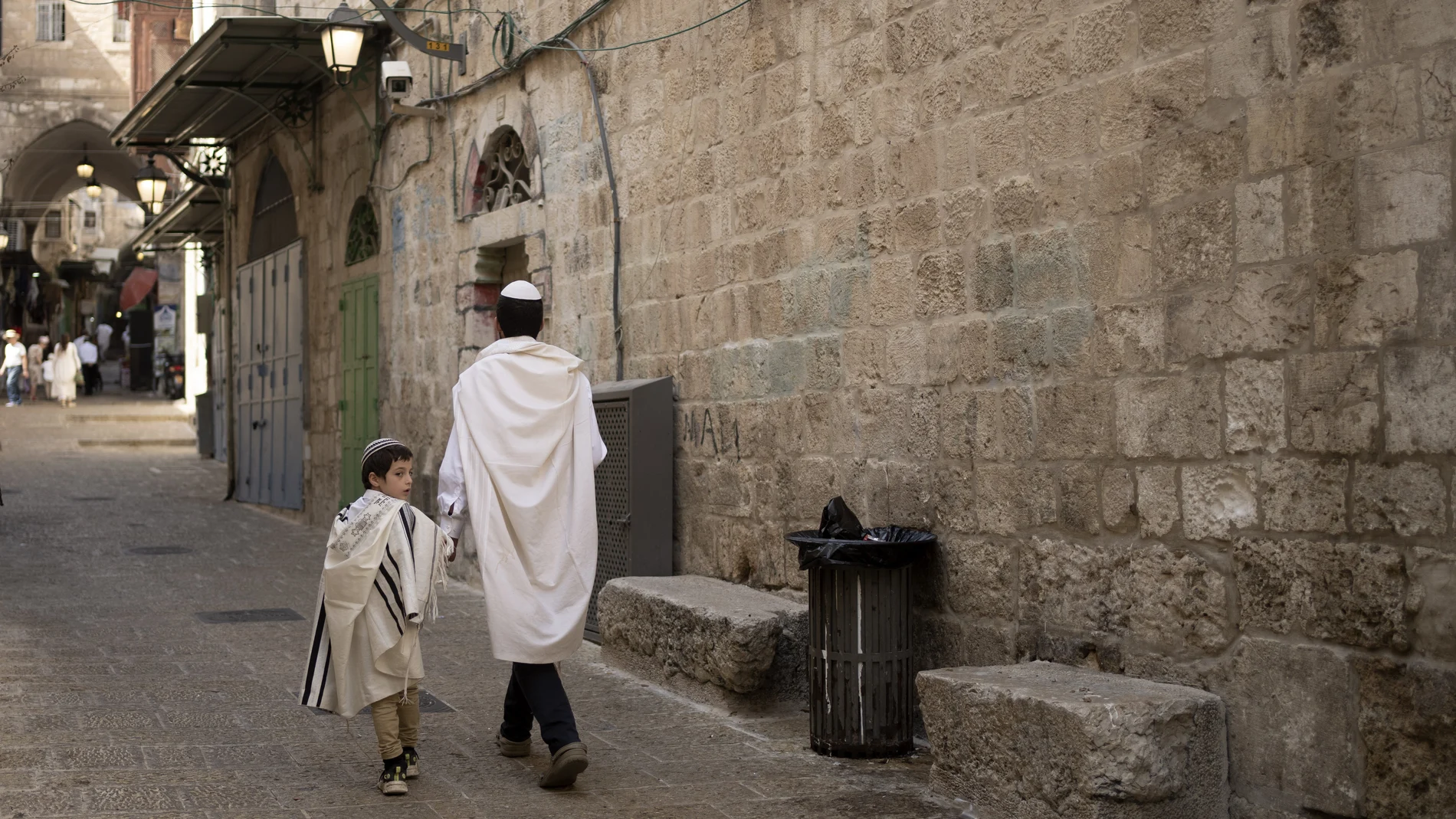 Un padre y un hijo judíos con mantones de oración caminan juntos en la Ciudad Vieja de Jerusalén en Yom Kippu, 5 de octubre de 2022. (AP Photo/ Maya Alleruzzo)