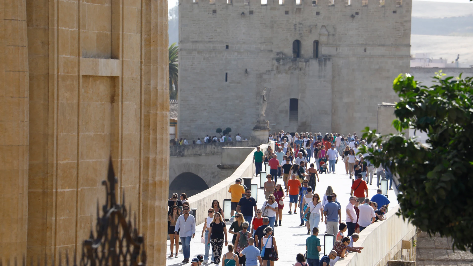 Varias personas pasean en Córdoba por el Puente Romano y la torre de la Calahorra