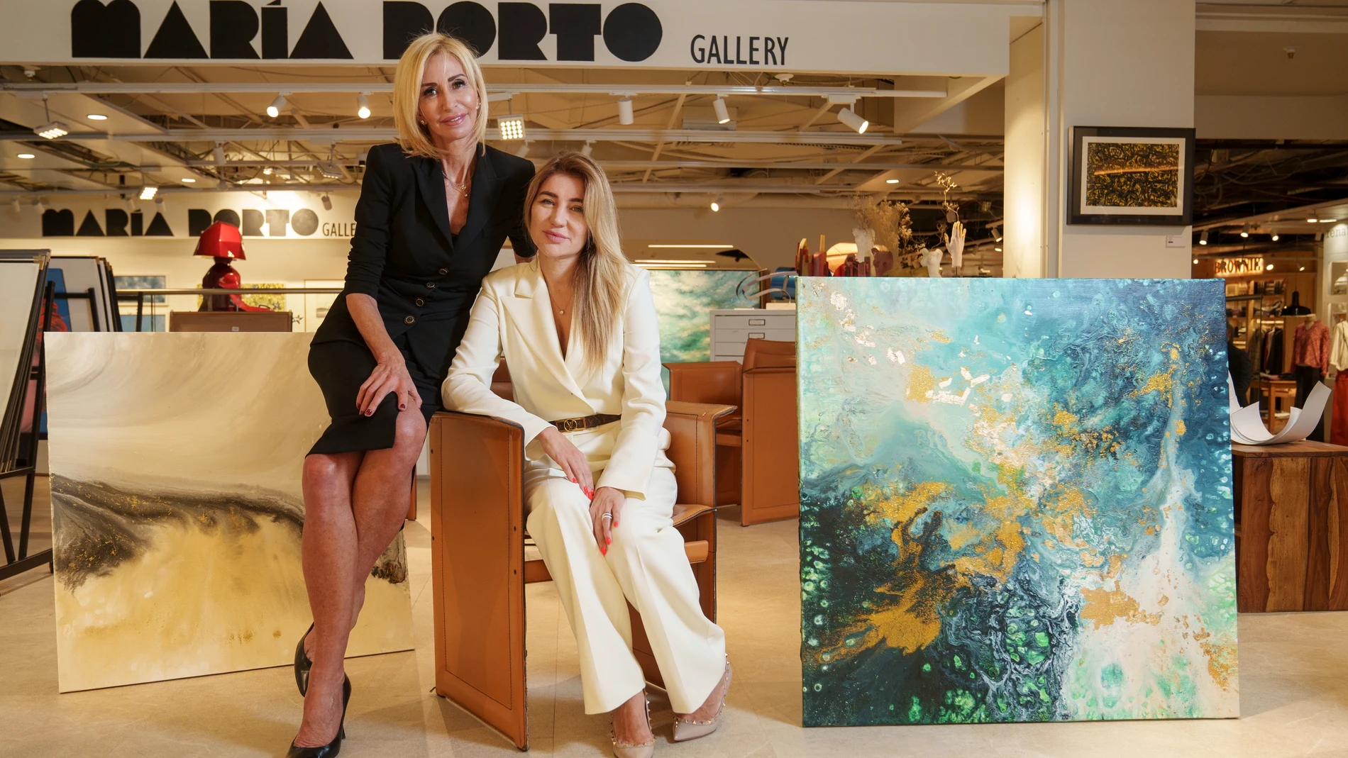 La galerista María Porto (izquierda) y la artista Elena Ksanti, en la Galería María Porto de Madrid junto a dos de los lienzos de Ksanti