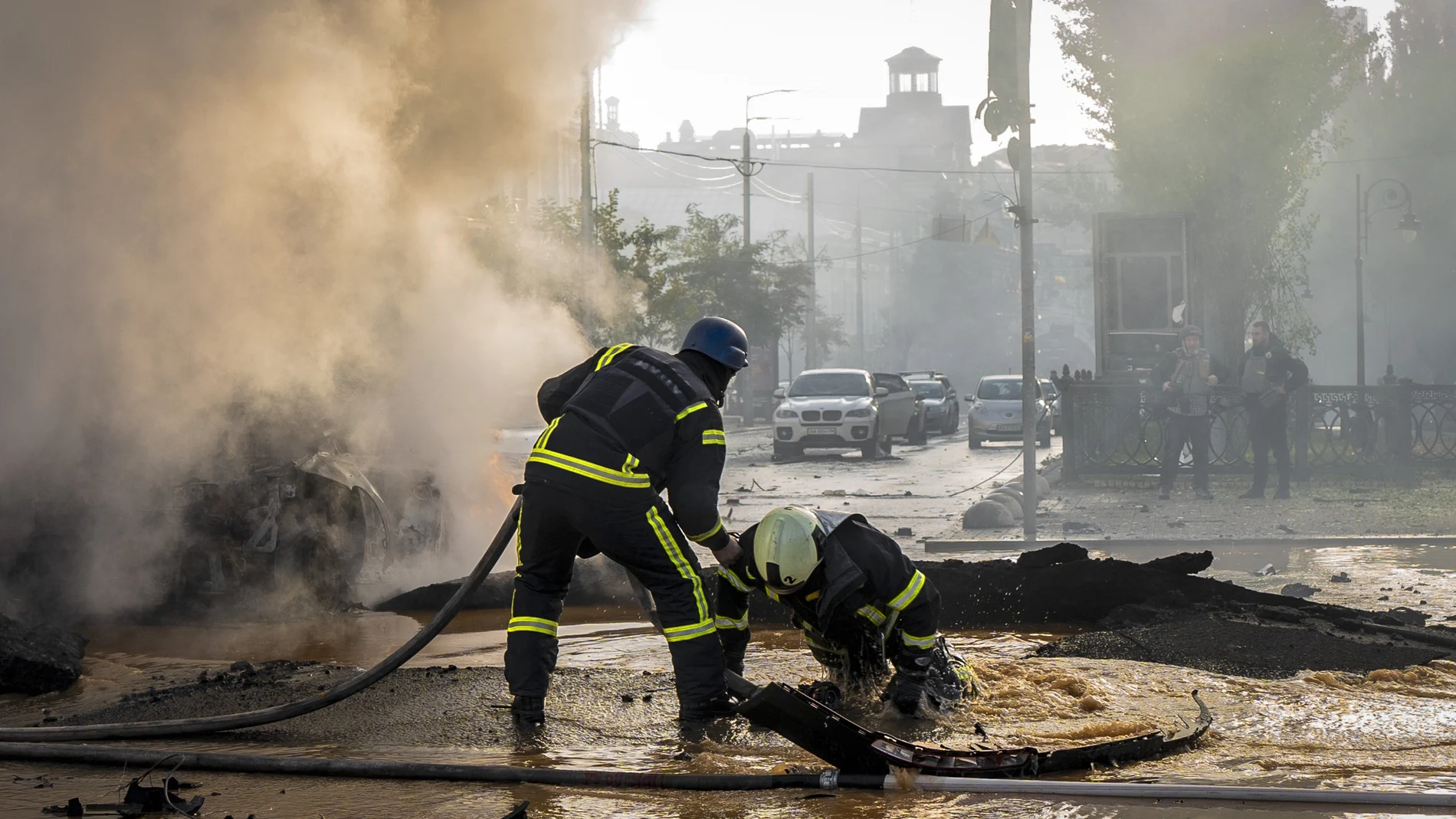 Un bombero ayuda a su compañero a salir de un agujero dejado por el impacto de los misiles en Kyiv