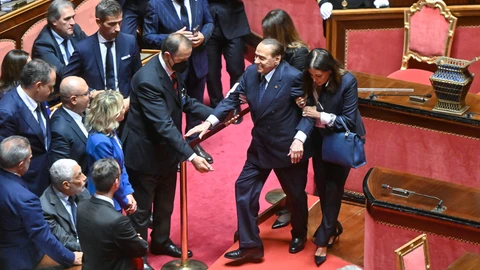 Los ujieres del Senado italiano ayudan ayer a Silvio Berlusconi a llegar a su escaño, en la Cámara Alta