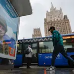 Un hombre pasa junto a un cartel propagandístico que dice «Gloria a los héroes de Rusia» con soldados en el frente