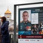 Mujeres rusas pasan frente a fotos de militares que lucharon en Ucrania durante una exposición callejera en Moscú