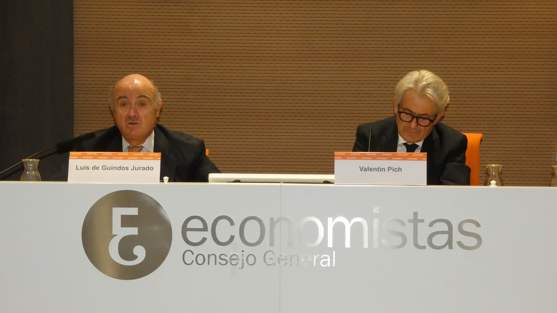 De izda. a dcha. Luis de Guindos, vicepresidente del Banco Central Europeo (BCE), y Valentín Pich, presidente del Consejo General de Economistas de España (CGE), durante durante la conferencia
