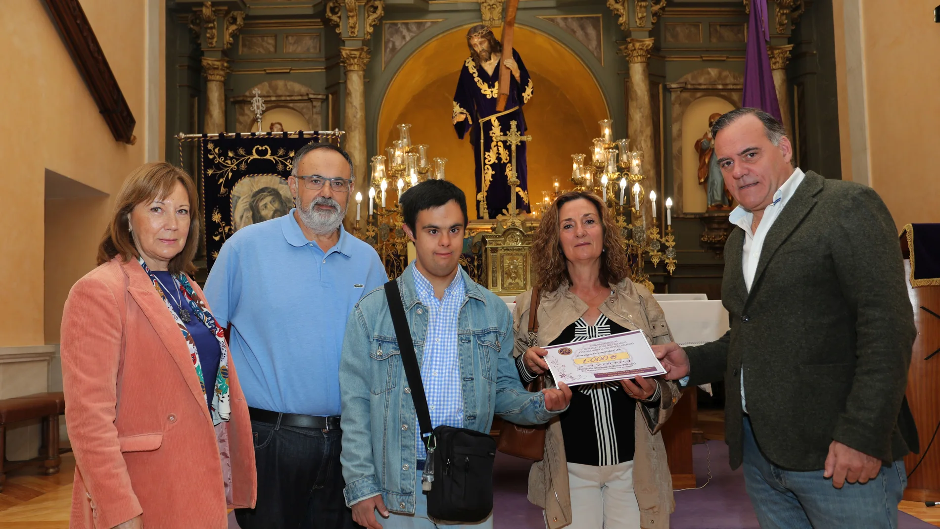 El hermano Mayor de la Cofradía, Domiciano Curiel (D) hace entrega de una donación de 1.000 euros a la presidenta de ASDOPA (Asociación de síndrome de Down de Palencia), Rosabel Obispo, entre otros