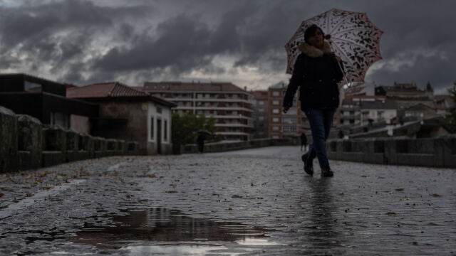 Una mujer se refugia de la lluvia con un paraguas