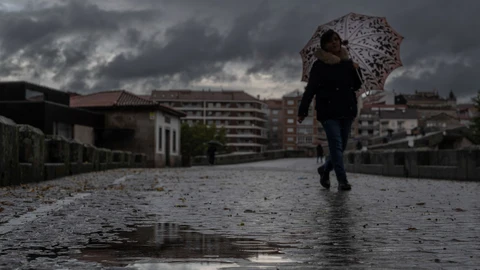 Una mujer se refugia de la lluvia con un paraguas