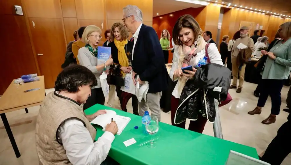 El doctor Carlos López-Otín firma libros a los asistentes a la conferencia