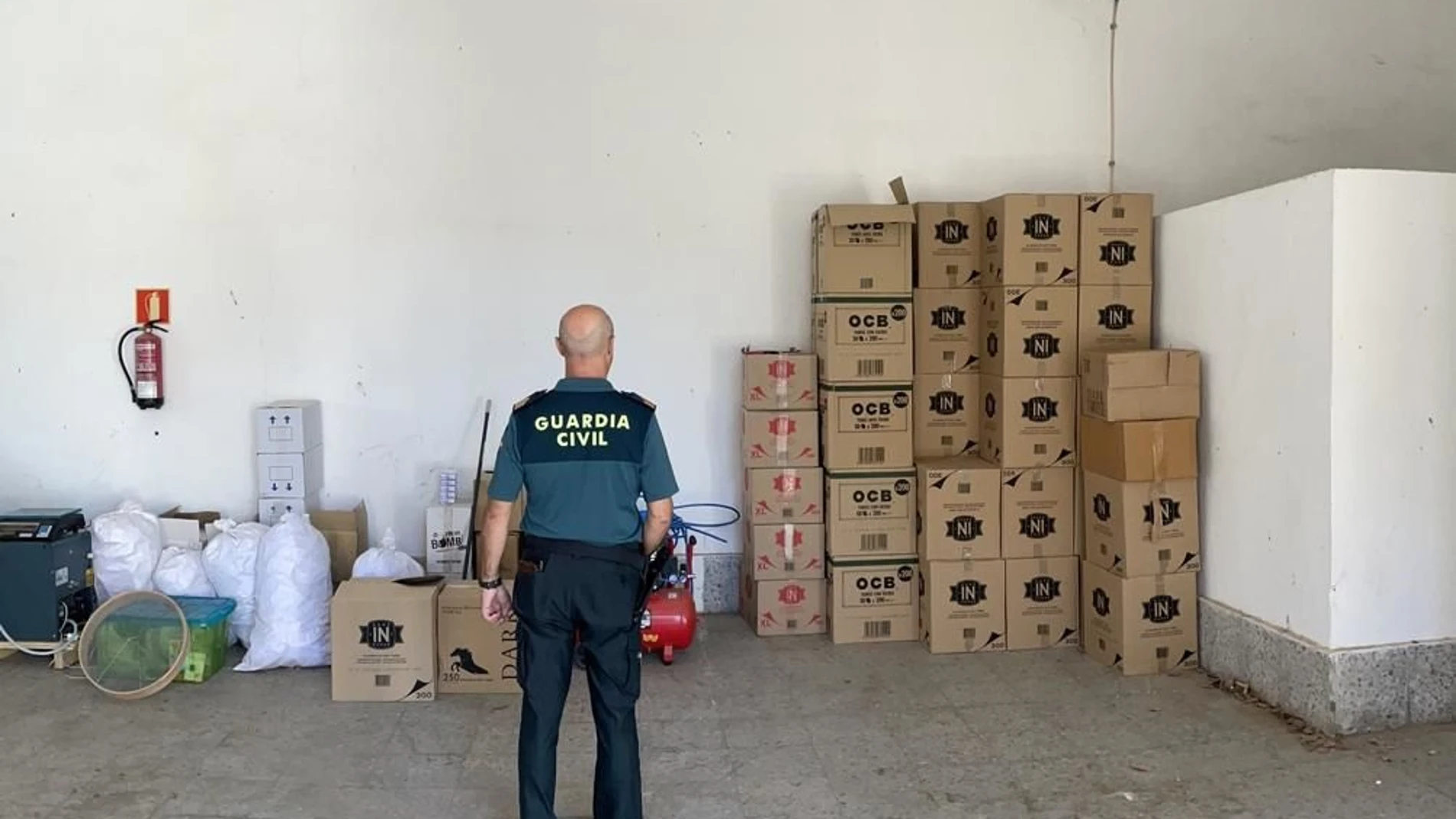 Un agente de la Guardia Civil en la nave usada para almacenar y fabricar tabaco de manera clandestina en Villaverde del Río, en Sevilla. GUARDIA CIVIL SEVILLA