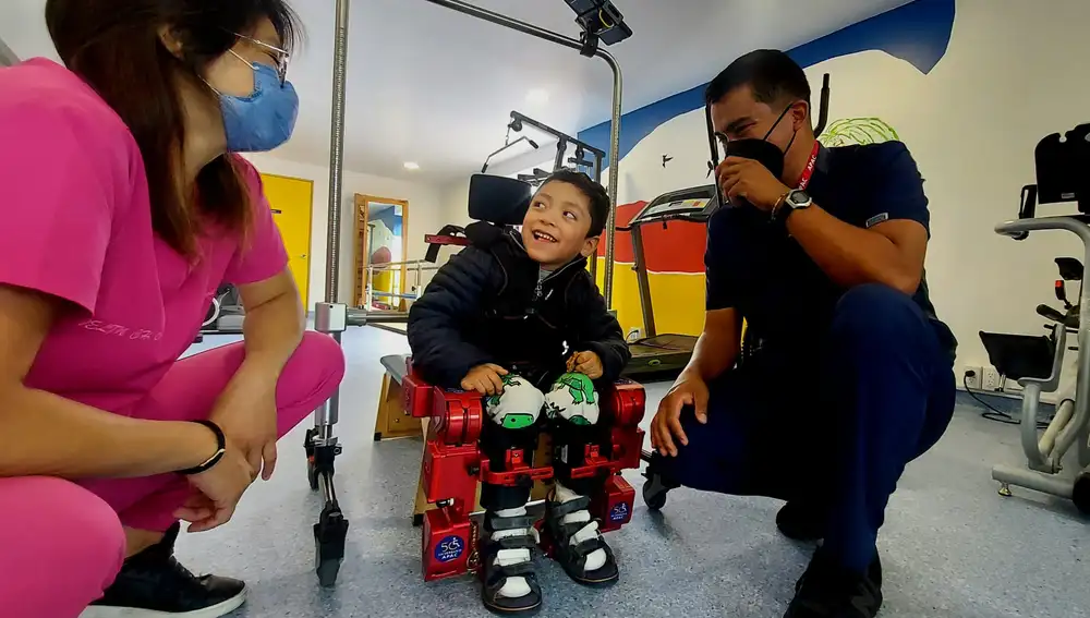 Fernando bromea con Evelin y Arturo, sus fisioterapeutas, después de caminar con el exoesqueleto Altas 2030 en la Clínica APAC en Ciudad de México.