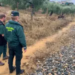 Dos agentes de la Guardia Civil ayudados por un perro especializado rastrean la zona cercana a la vía del tren en Villanueva del Río y Minas (Sevilla). EFE/Fermín Cabanillas