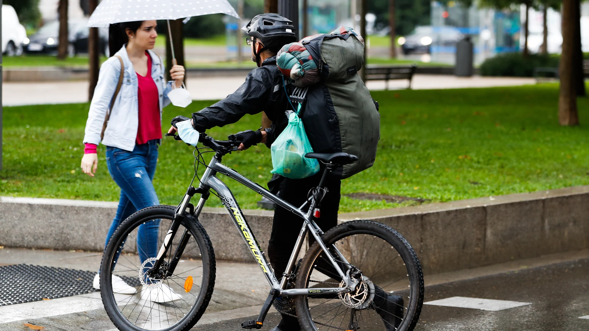 Una viandante y un ciclista se cruzan tras un chaparrón caído en Madrid