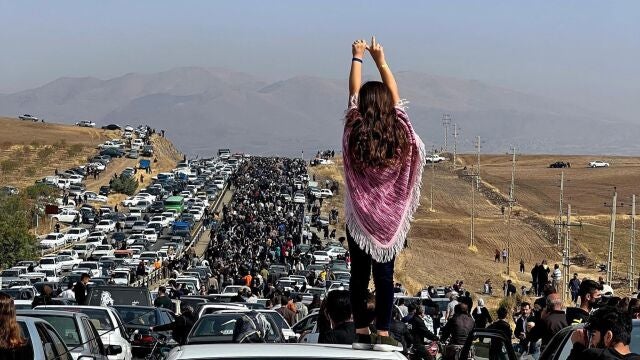 Una mujer sin velo encima de un vehículo mientras miles de personas se dirigen al cementerio de Aichi en Saqez, la ciudad natal de Mahsa Amini en la provincia occidental iraní del Kurdistán, para conmemorar los 40 días de su muerte