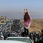 Una mujer sin velo encima de un vehículo mientras miles de personas se dirigen al cementerio de Aichi en Saqez, la ciudad natal de Mahsa Amini en la provincia occidental iraní del Kurdistán, para conmemorar los 40 días de su muerte