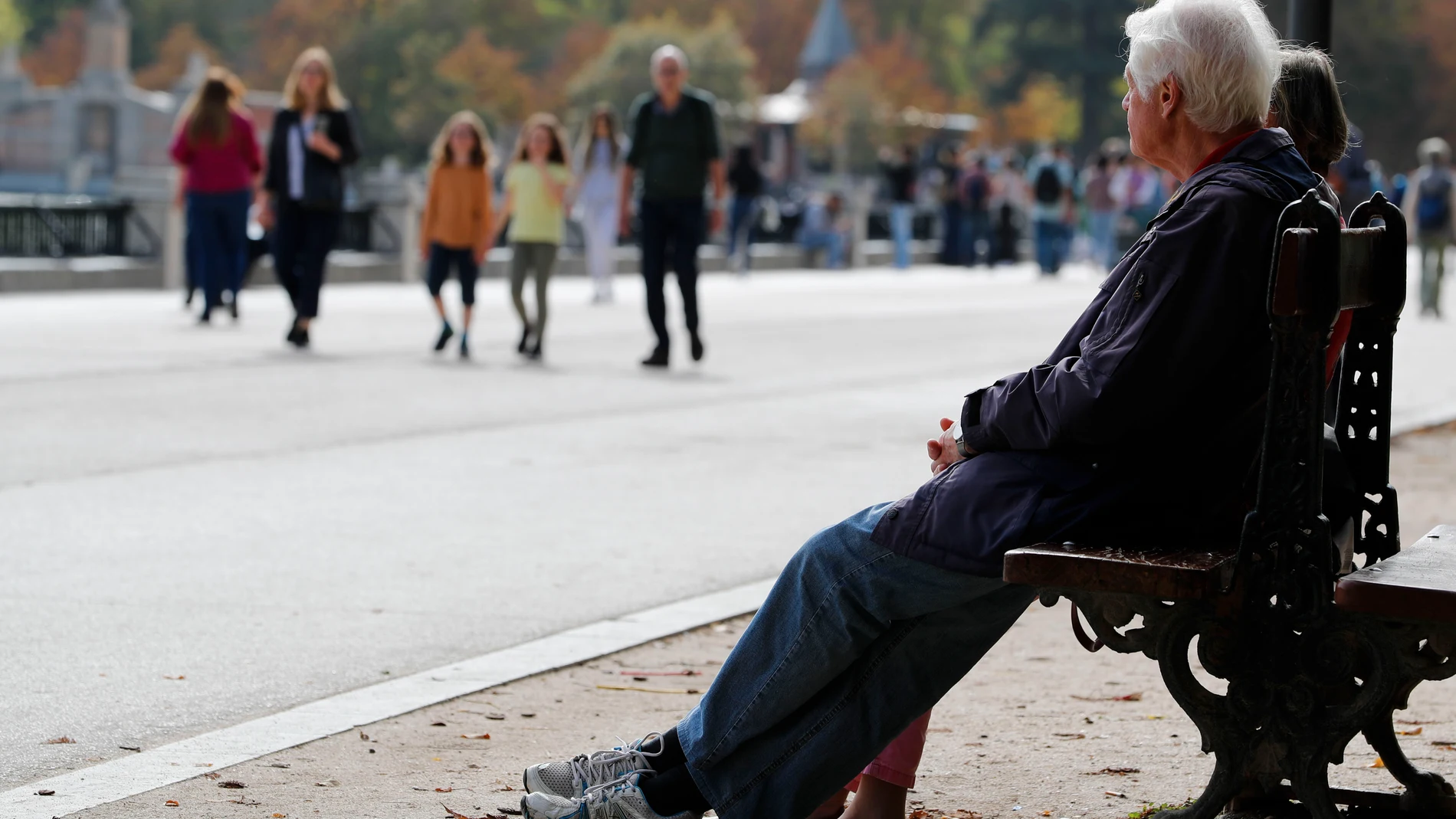 Varias personas descansan en un banco del parque de El Retiro de Madrid