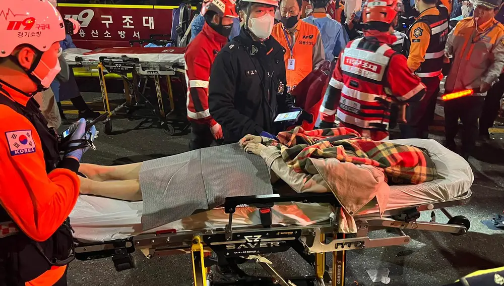Los servicios de emergencia trasladan a una persona herida en una camilla en el distrito de Itaewon de Seúl después de una estampida durante las fiestas de Halloween