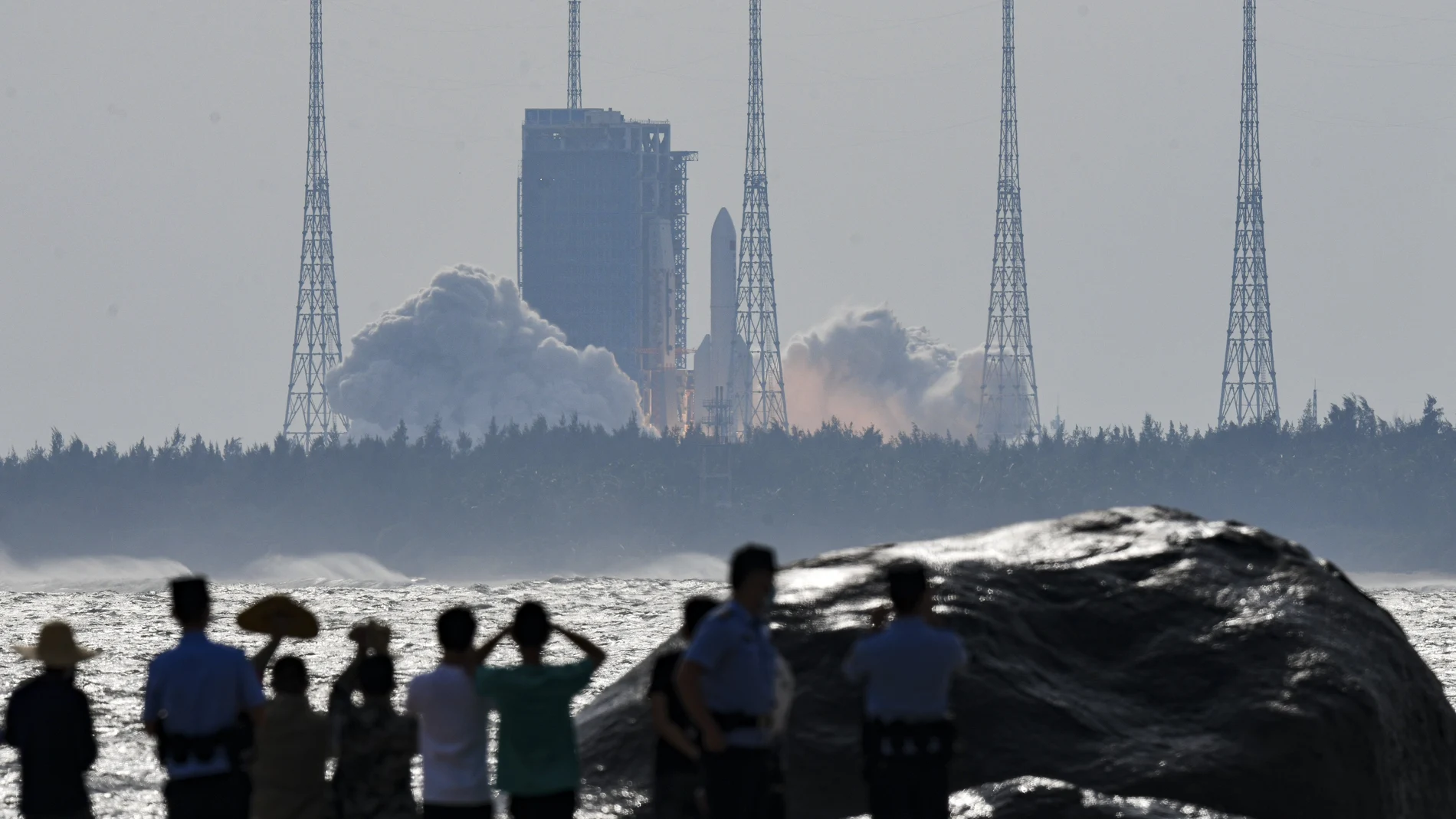 In this photo released by Xinhua News Agency, people watch the Long March-5B Y4 carrier rocket carrying the space lab module Mengtian, blasts off from the Wenchang Satellite Launch Center in south China's Hainan Province, Monday, Oct. 31, 2022. China has launched the third and final module to complete its permanent space station, realizing a more than decade-long endeavor to maintain a constant crewed presence in orbit. (Yang Guanyu/Xinhua via AP)