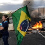 Una mujer sostiene una bandera de Brasil durante bloqueo de camioneros en la carretera Presidente Dutra para apoyar a Bolsonaro