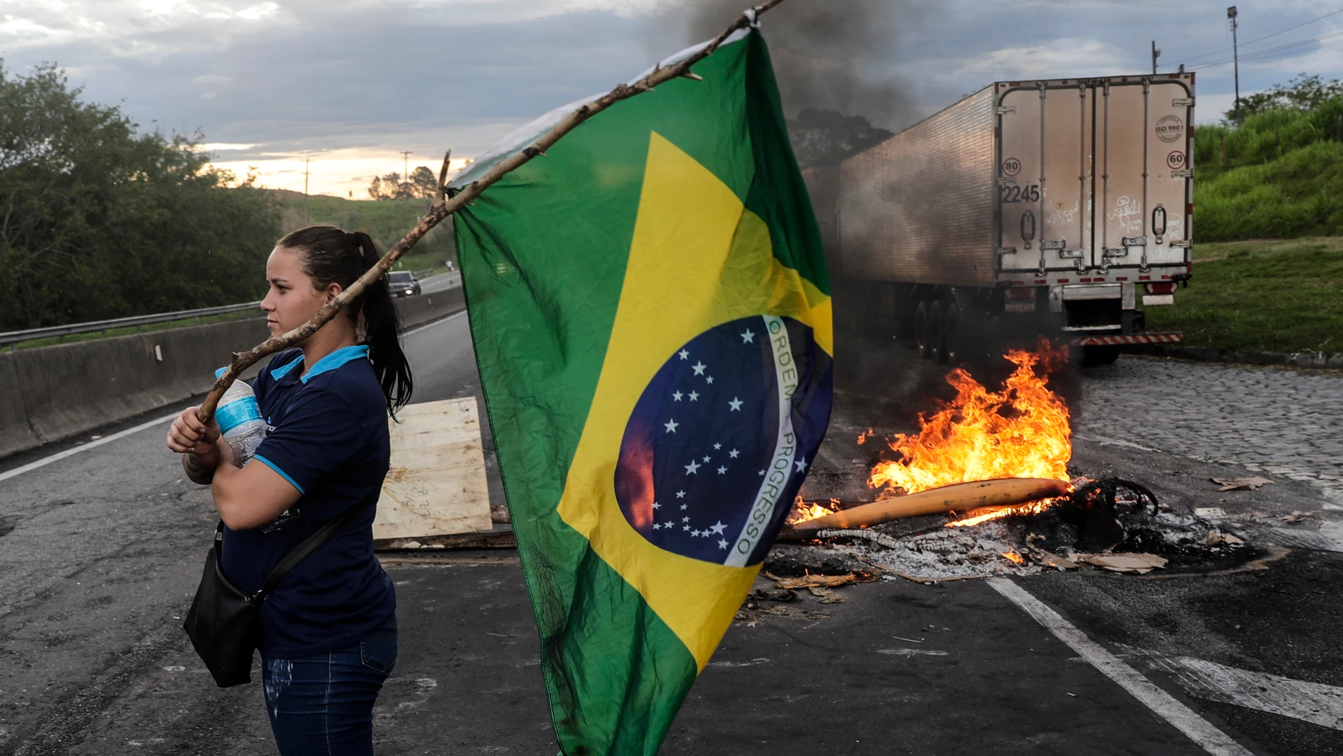 Una mujer sostiene una bandera de Brasil durante bloqueo de camioneros en la carretera Presidente Dutra para apoyar a Bolsonaro