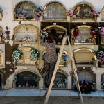 Una mujer coloca un ramo de flores en la lápida de un ser querido en un cementerio en Barcelona el Día de todos los Santos