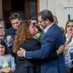 La tía de la niña asesinada junto al padre de la niña asesinada se abrazan durante un homenaje y minuto de silencio por la niña, en la Plaza Mayor de Torrecaballeros (Segovia)