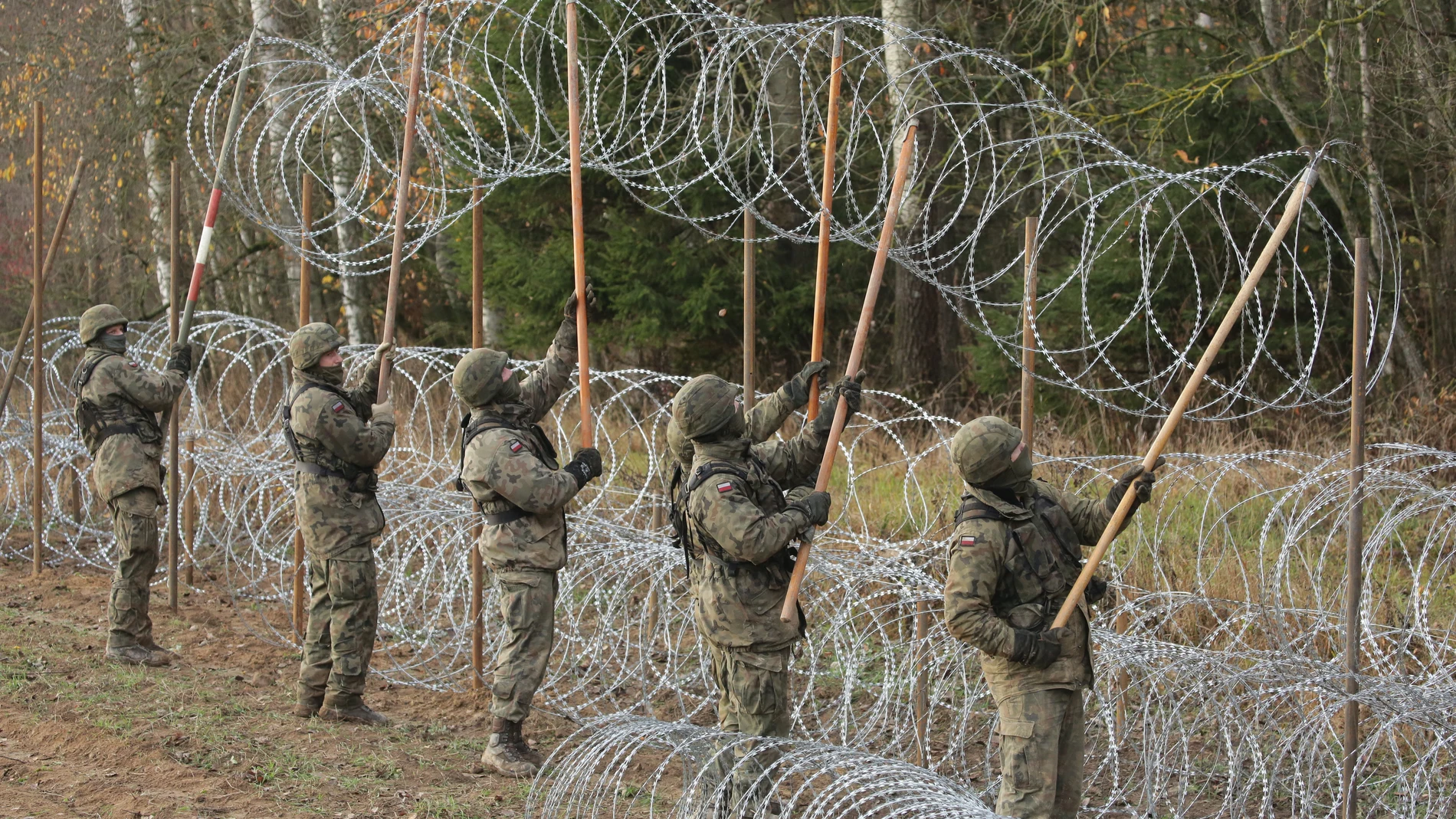 Soldados polacos instalan este miércoles alambre de espino a lo largo de la frontera polaca con el exclave ruso de Kaliningrado, cerca del pueblo de Zerdziny
