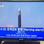La gente ve las noticias sobre una alarma antiaérea en Seúl tras el disparo de diez misiles desde Corea del Norte