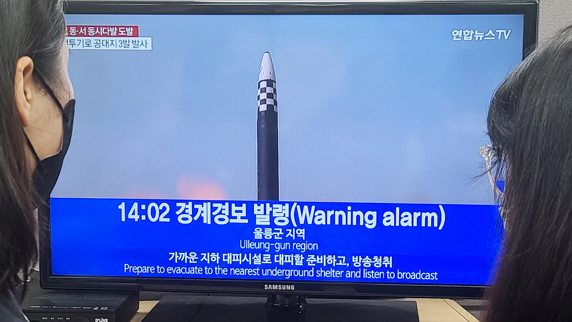 La gente ve las noticias sobre una alarma antiaérea en Seúl tras el disparo de diez misiles desde Corea del Norte