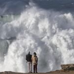 Unos turistas observan el oleaje en Muxía donde han llegado olas gigantes