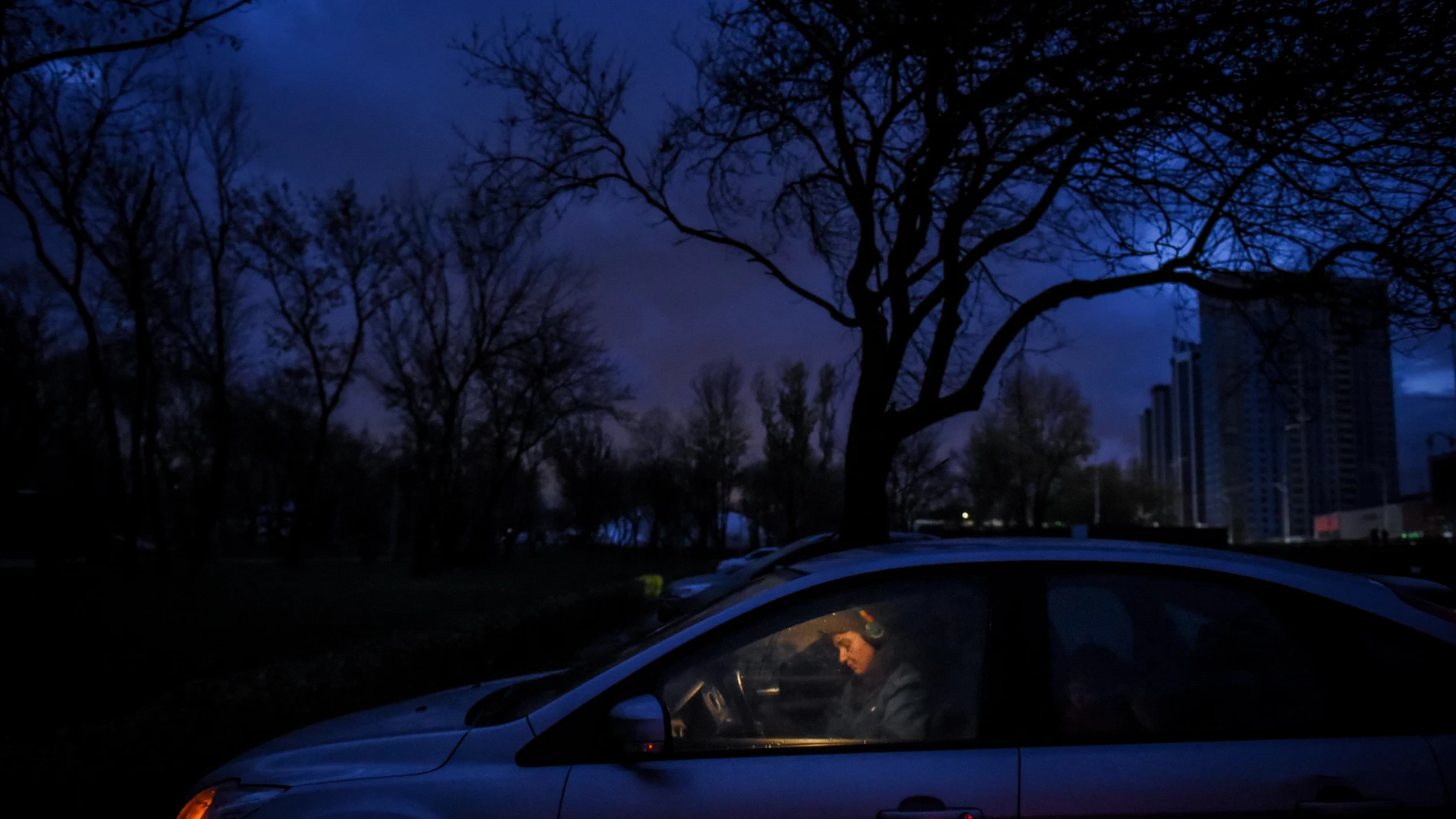 Una mujer se sienta en un coche después de que las luces se apagaran debido a los cortes de energía programados que se introdujeron en Kyiv