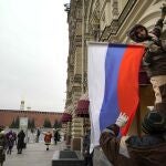 Trabajadores municipales colocan una bandera rusa en una tienda estatal en Moscú