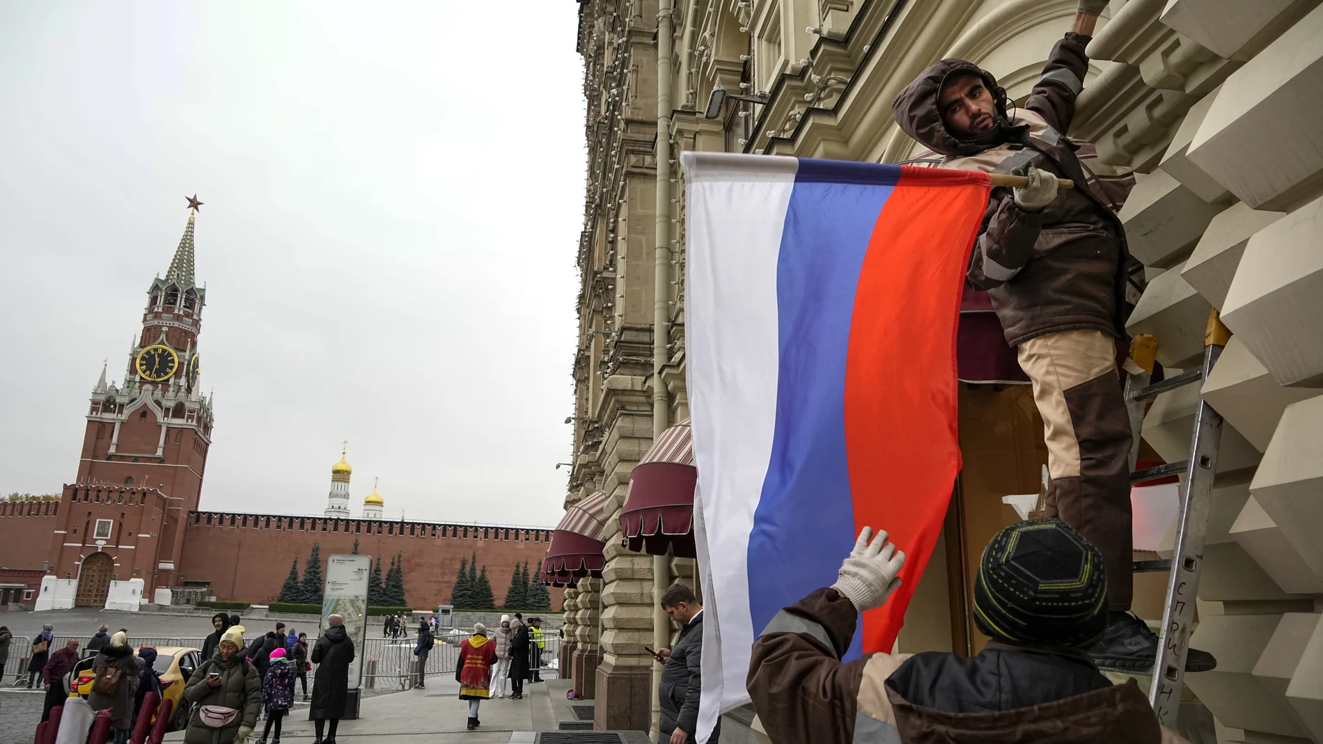 Trabajadores municipales colocan una bandera rusa en una tienda estatal en Moscú